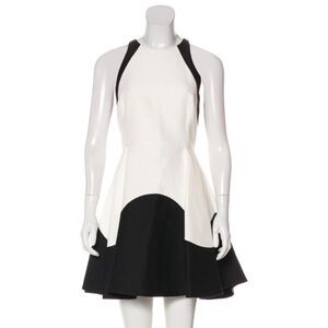 White and black mini dress with crew neck, pleated hem and zip closure at back.